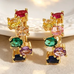 Close-up of gold-tone earrings with multi-colored oval-cut gemstones.