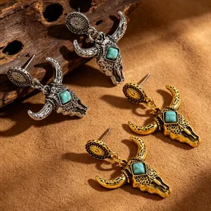 Dettaglio di orecchini vintage a forma di teschio di toro con pietre turchesi in oro e argento