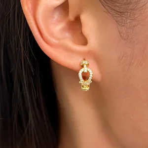 Close-up shot of an elegant gold horseshoe earring with sparkling stones worn on an ear