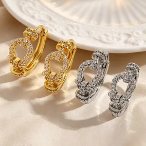 Close-up of elegant gold and silver heart-shaped hoop earrings with sparkling zircons