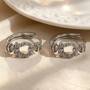 Detailed view of silver hoop earrings with shimmering zircon horsebit link design on silk