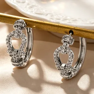 Macro detail of silver hoop earrings featuring sparkling heart-shaped pave zircon settings.