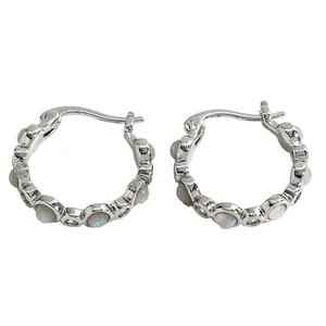 Close-up detail of silver-toned hoop earrings with white opal-like stone inlays