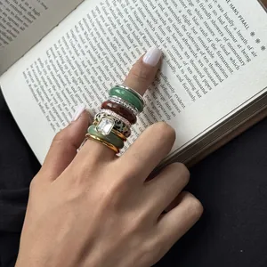 Detailed close-up shot of stacked natural stone and stainless steel rings on finger.