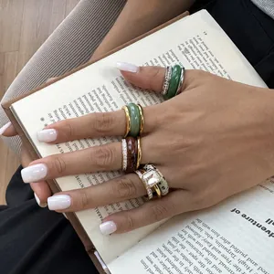 Detailed view of stacked natural stone and gold-plated stainless steel rings on hand