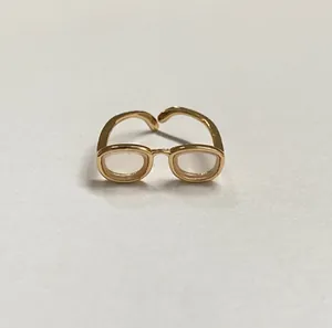 Détail d'une bague créative dorée originale arborant un design de lunettes miniatures