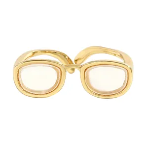 Vue détaillée de la bague ouverte dorée unique en forme de mini-lunettes créatives.