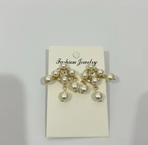 Detail view of elegant gold pearl tassel earrings with rhinestones on a display card