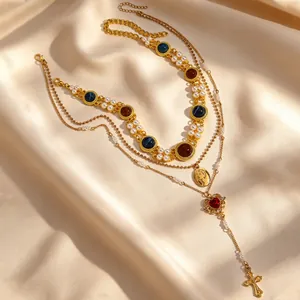 Detailed view of layered gold necklace with heart, cross pendants and pearls.