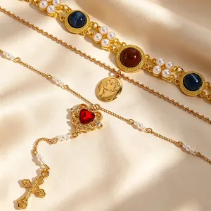 Detailed close-up of a vintage gold cross and red heart pendant necklace with pearls