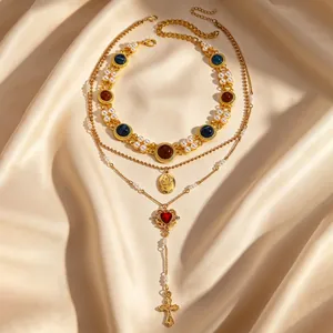 Detail view of layered gold necklace with pearls, heart gem, and cross pendant