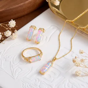 Elegantes Opal-Schmuckset mit goldenem Ring, Ohrringen und Halskette auf weißem Grund