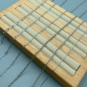 Detail view of various stainless steel chain styles for DIY jewelry on wooden display