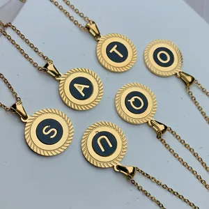 Detailaufnahme von runden goldfarbenen Edelstahlanhängern mit Initialen und schwarzem Inlay