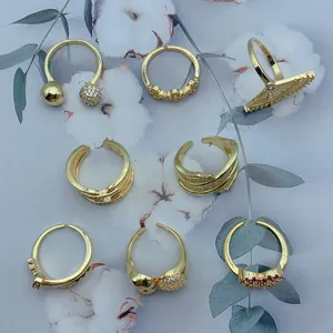 Detailed view of multiple gold-plated open rings with micro-pave zirconia and retro motifs