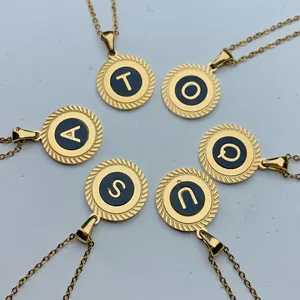 Detailansicht verschiedener goldener Edelstahl-Buchstabenanhänger mit schwarzer Emaille