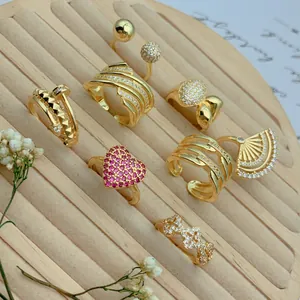 Close-up of vintage gold-plated rings with micro-set zircons in heart and fan shapes.