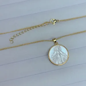 Primer plano detallado del colgante de nácar de la Virgen María con cadena de oro