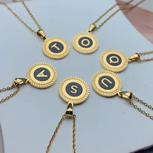 Nahaufnahme von runden Goldanhängern aus Edelstahl mit schwarzen Buchstabeneinsätzen auf Basis