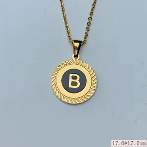 Nahaufnahme eines kreisförmigen Goldanhängers mit schwarzem Emaille-Kern und dem Buchstaben B.