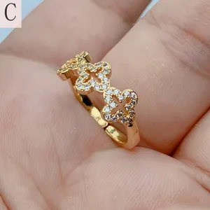 Detail view of a gold-plated open ring featuring cubic zirconia clover patterns.