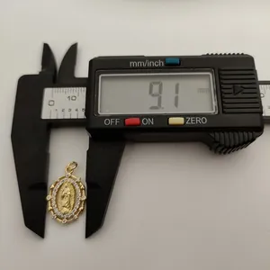 Detailed close-up of a Virgin of Guadalupe pendant being measured at 9.1mm with a digital caliper.