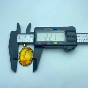 Macro detail showing a 22.1mm measurement of a vintage oval amber resin pendant