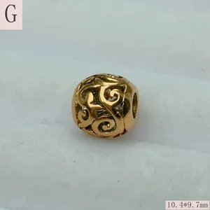 Macro view of a gold stainless steel filigree hollow bead, measuring 10.4x9.7mm.
