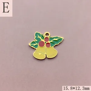 Close-up of golden enamel Christmas bells charm with holly leaves and red berries for DIY