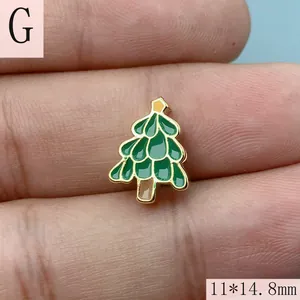 Gros plan d'une breloque sapin de Noël en émail vert avec étiquette de taille 11x14,8mm.