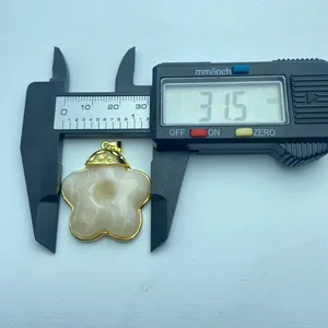 Detail shot of a vintage flower resin pendant with a caliper showing 31.5mm size