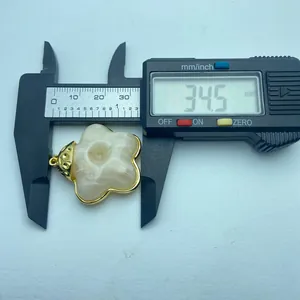 Close-up measurement of vintage resin flower pendant with gold trim, 34.5mm width