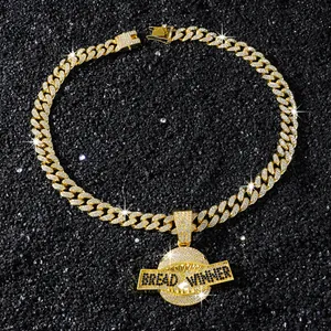 Detail van een goudkleurige Cubaanse schakelketting met haaienmond hanger en steentjes