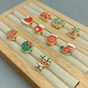Detailed view of festive Christmas themed enamel beads with gold finish on jewelry tray.