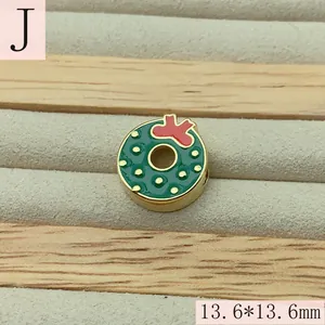 Close-up of a green enamel Christmas wreath charm with a red bow for DIY jewelry making