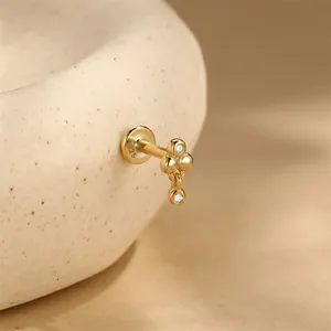 Primo piano di un orecchino a perno in argento S925 con pallina dorata e piccoli diamanti.