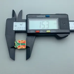 Close-up of Christmas gift box charm measured with a digital caliper showing 15.3 mm