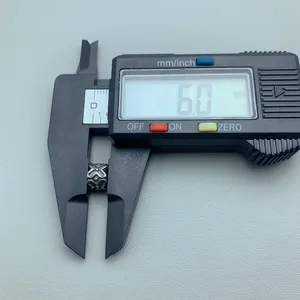 Close-up of a 6mm stainless steel patterned spacer bead measured with a digital caliper