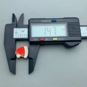Macro detail of a digital caliper measuring a red enamel Christmas hat charm at 14.7 mm width