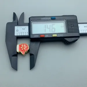 Close-up showing a digital caliper measuring a red Christmas mitten charm with gold detail