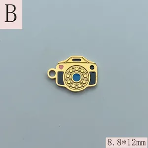 Detailed view of a small golden camera charm pendant with colorful enamel accents