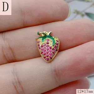 Primer plano de un dije de fresa con circones rosas y esmalte verde para joyería DIY