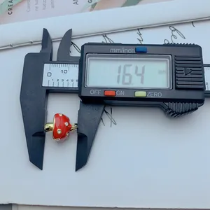 Primer plano de la medición de un colgante de hongo rojo con un ancho de 16,4 mm.