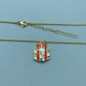 Nahaufnahme einer Weihnachtshalskette mit Geschenk-Anhänger, bunten Zirkonen und Goldkette.