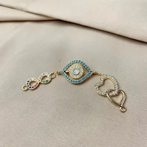 Detail view of gold-plated infinity, evil eye, and heart charms with cubic zirconia
