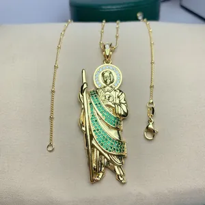Detailopname van gouden Sint-Judas hanger met groene zirkonia steentjes aan een schakelketting.