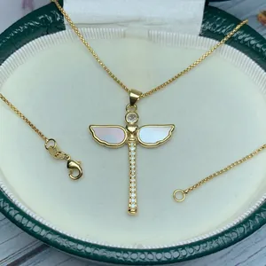 Detalle de un colgante de libélula dorada con alas de nácar natural y circonitas blancas.