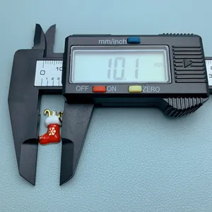 Digital caliper measuring a red enamel Christmas stocking charm with zircon detail.