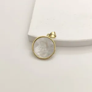 Detail of a round gold pendant featuring a shimmering white mother of pearl inlay.