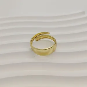 Close-up van een minimalistische goudkleurige geometrische open ring op een gegolfd wit oppervlak